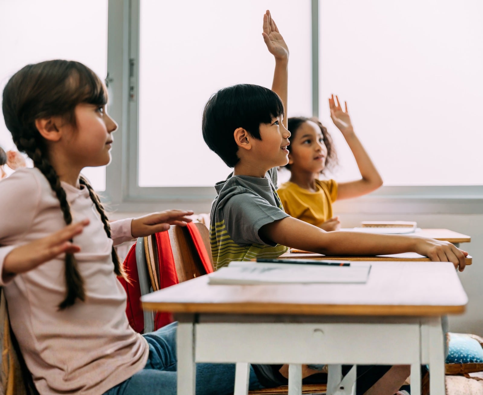 子どもたちが教室で手を挙げている様子